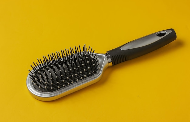 Stylish hairbrush on yellow background