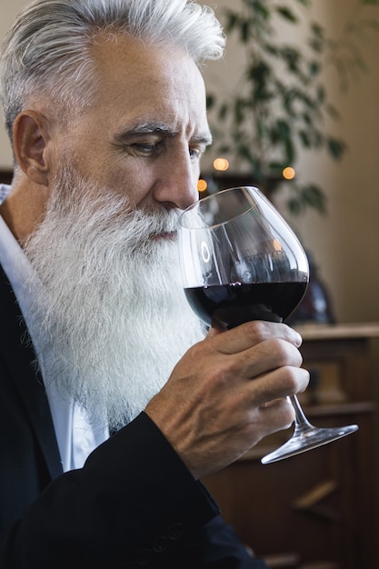 Foto uomo anziano barbuto elegante e bello che beve vino rosso