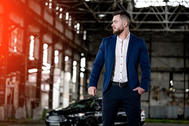 Stylish handsome businessman standing by. Young succesfull businessman looking through.