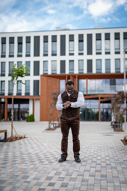 Stylish handsome man in casual cloth looking at the watches in urban street of city. Elegant trendy lifestyle vogue