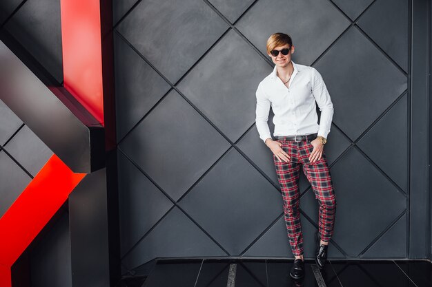 Stylish handsome man standing near modern black building.