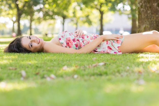 芝生の上に横たわるスタイリッシュな幸せなブルネット