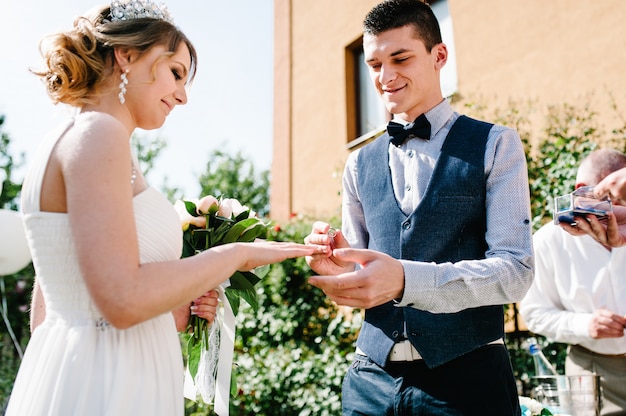 Stylish happy groom wear gold ring on the finger of the bride.