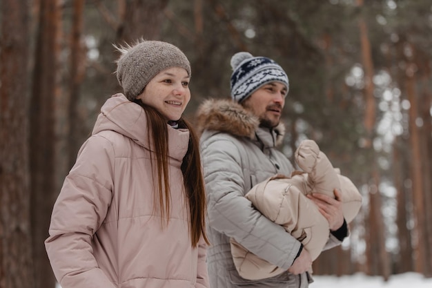 Stylish happy young family walks with baby on winter forest park family pastime