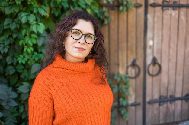 Stylish happy young woman wearing orange sweatshirt and eyeglasses Portrait of smiling girl in trendy eyeglasses in city copy space and empty space for advertising