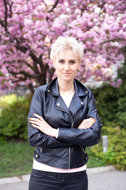 Stylish hipster woman near pink sakura blooming tree