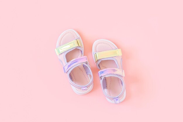 Stylish holographic sandals for kids on pink background Shiny fashion summer shoes Flat lay Top view