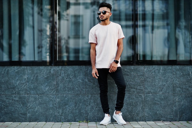 Stylish indian beard man at pink tshirt sunglasses India model posed outdoor at streets of city