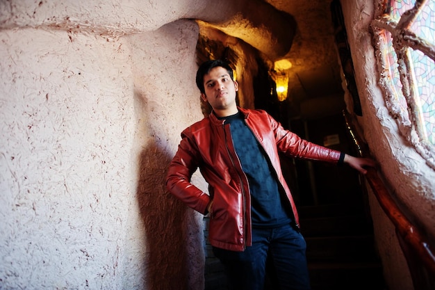 Stylish indian man in casual wear posing on stairs of house against window