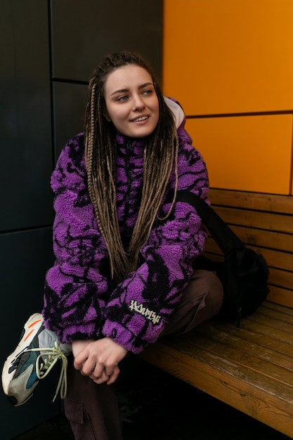 Photo stylish informal woman with dreadlocks dressed in a purple jacket walks through the city in winter