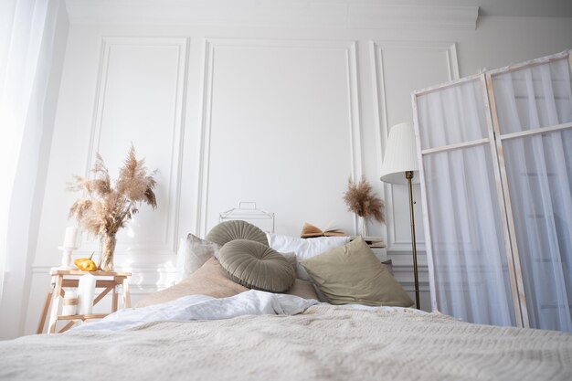 Stylish interior of comfortable bedroom. Cozy apartment in soft beige and white colors.