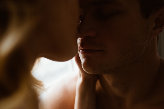 Stylish interior. A couple near the window, under one blue blanket of large mating. Love story.