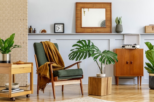 Stylish interior of living room with design armchair, wooden vintage commode, round mirror, shelf, tropical leaf, coffeee table, decoration, carpet and persnoal accessories in home decor.