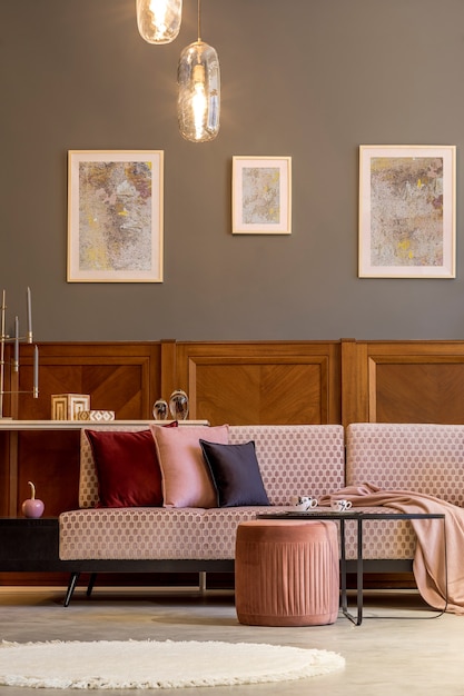 デザインピンクのベルベットのソファエレガントなプーフコーヒーテーブルのポスターとリビングルームのスタイリッシュなインテリア植物枕の装飾とパーソナルアクセサリーモダンな家の装飾とホームステージング