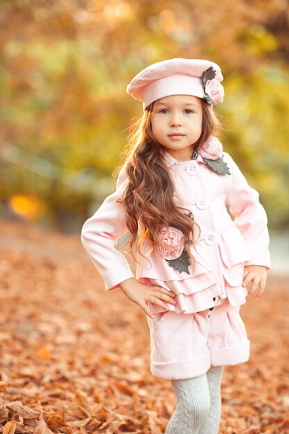 Stylish kid girl wearing trendy coat and hat outdoors Looking at camera