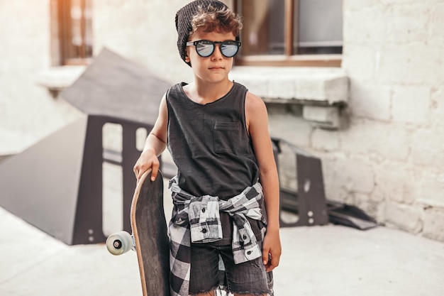 Photo stylish kid with skateboard on street