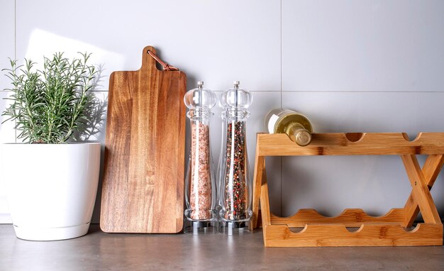 Stylish kitchen interior design with wooden cutting board pepper and salt mill plant rosemary top view