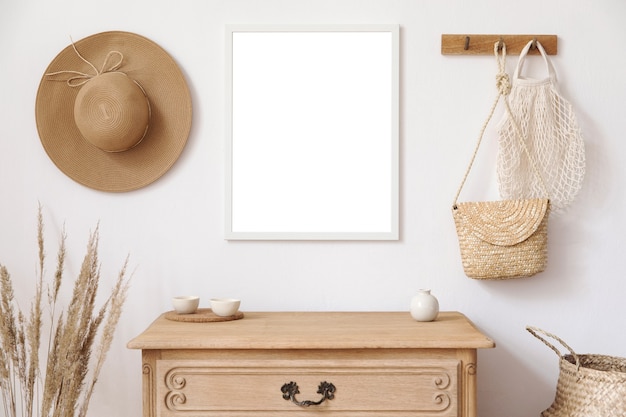 Stylish korean interior of living room with mock up poster frame, elegant accessories, dried flowers in vase, wooden shelf and hanging rattan leaf bags. Minimalistic concept of home decor. Template.