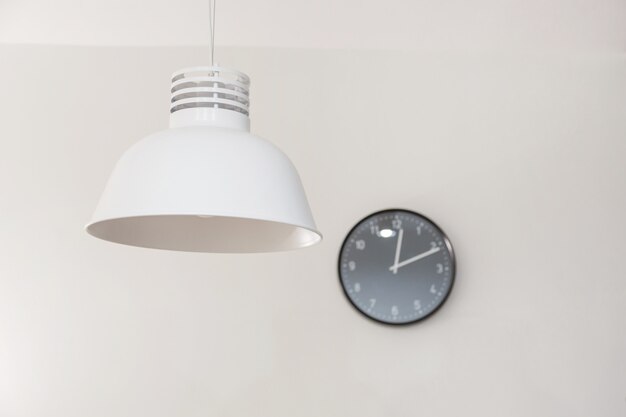 Stylish lamp and clock on wall.