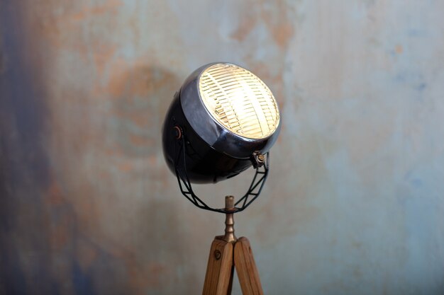 Stylish lamp on tripod in room.