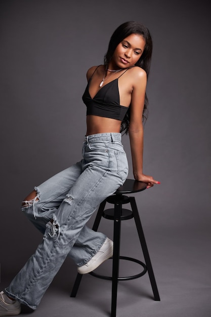 Stylish latin american woman leaning on stool