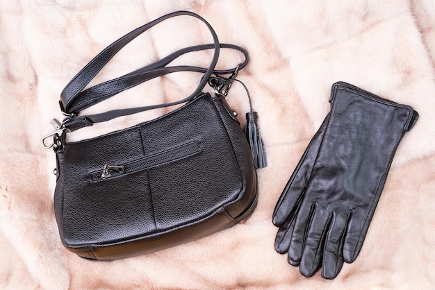 Stylish leather gloves and bag on fur background, fashion.