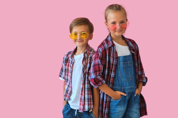 Stylish little girl and boy in color sunglasses dressed in plaid shirts