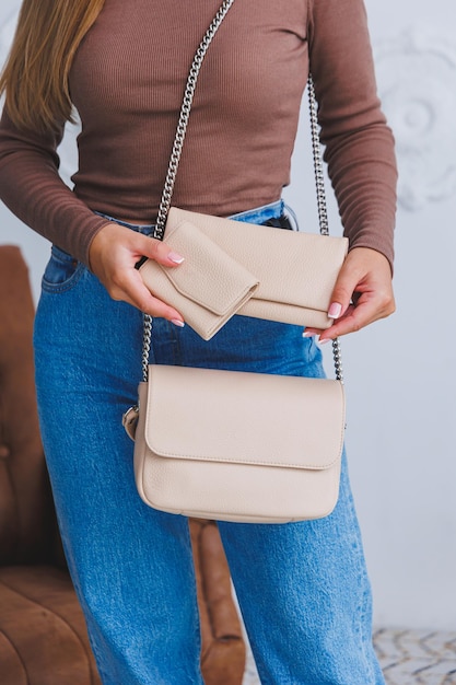 Look elegante primo piano della borsetta beige nelle mani ragazza alla moda closeup foto di una ragazza con una borsetta nelle sue mani