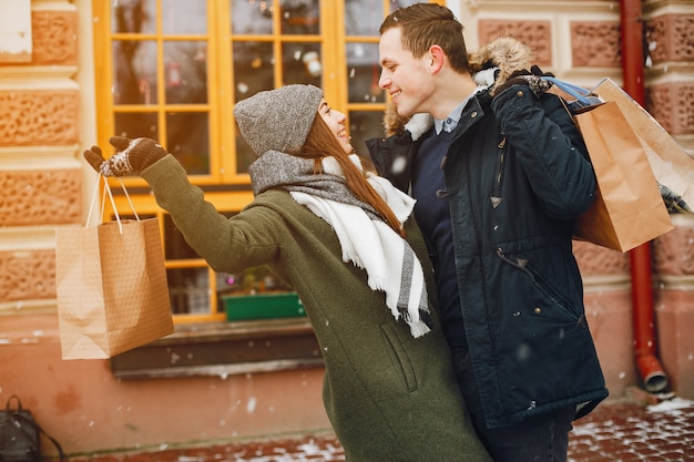 stylish loving couple standing in spring city near building with shopping bags