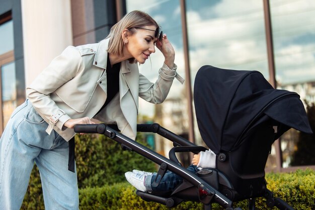 Photo stylish loving mom walks with a stroller in the city location maternity lifestyle