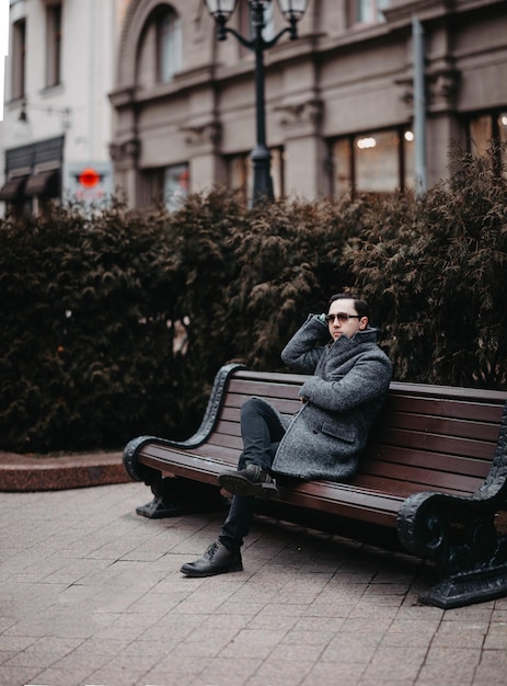 stylish man in a gray coat and sunglasses walking in the city.
