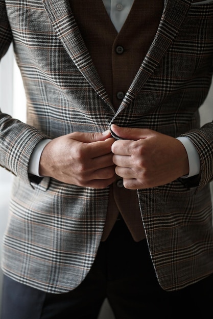 Stylish man groom buttoning a button on his jacket