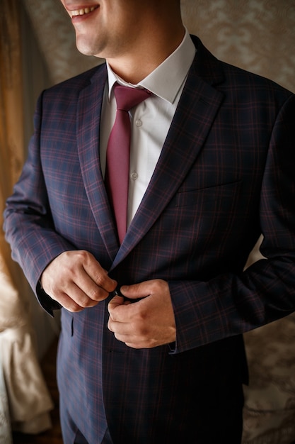 Stylish man groom buttoning a button on his jacket