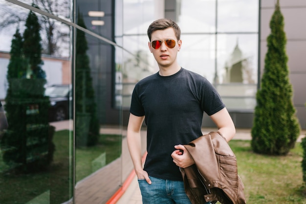 A stylish man in leather jacket, glasses and black T-shirt. Street photo