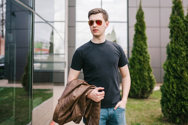 A stylish man in leather jacket, glasses and black T-shirt. Street photo