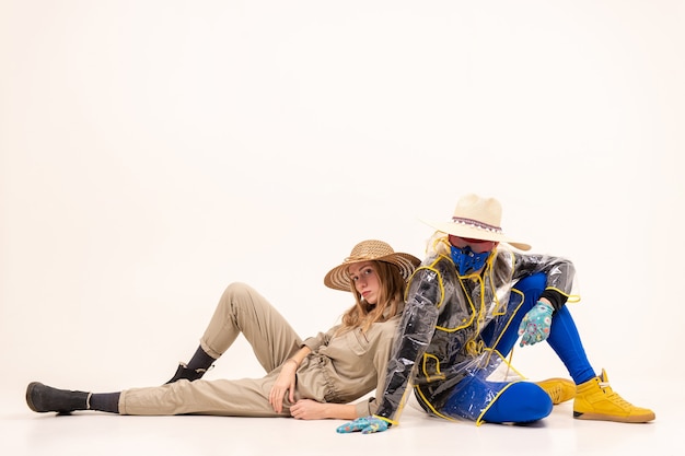 Stylish man in the mask and woman in straw hats posing over white background