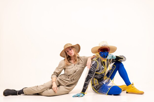 Stylish man in the mask and woman in straw hats posing over white background