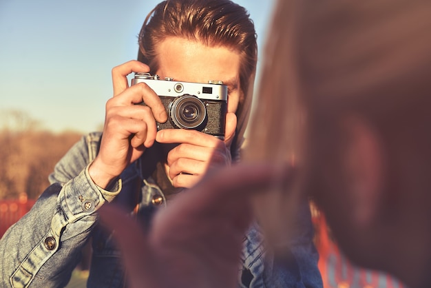 Stylish man photographing a woman on retro camera in the street