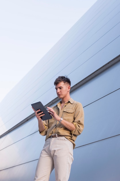 Photo stylish man posing outdoors while looking at tablet