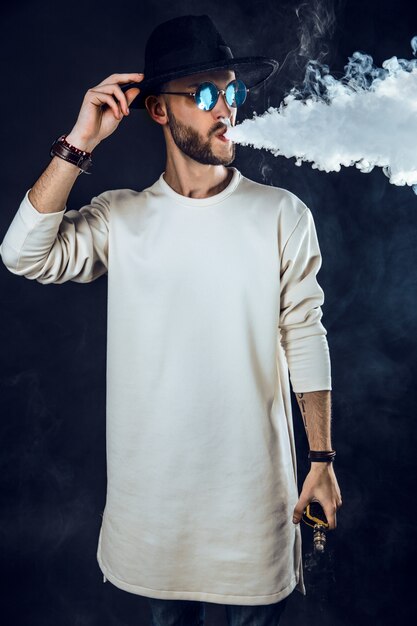 Stylish man puffing vapor