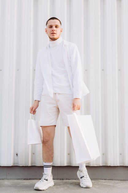 A stylish man wearing white after Black Friday shopping