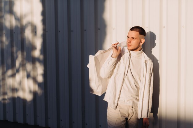 A stylish man wearing white after Black Friday shopping