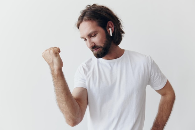 Stylish man in a white tshirt with wireless headphones in his ears having fun listening to music smile on a white background lifestyle