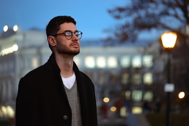 Photo stylish man with a beard and in sunglasses standing in the park.