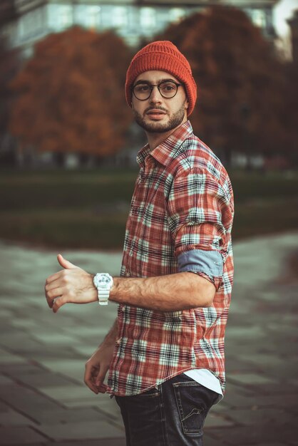 Stylish man with a beard and in sunglasses standing in the park.