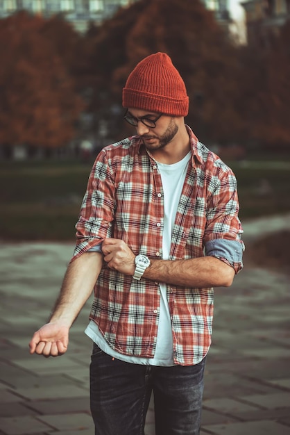 Stylish man with a beard and in sunglasses standing in the park.