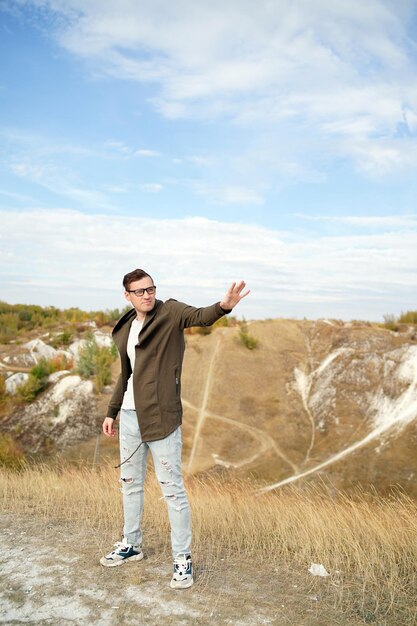 Stylish man with glasses in cape shows psychic Adult male with eyeglasses poses standing in hilly terrain