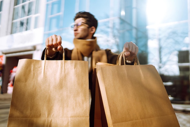 Uomo alla moda con pacchetti di carta dopo lo shopping concetto di stile di vita consumista di vendita