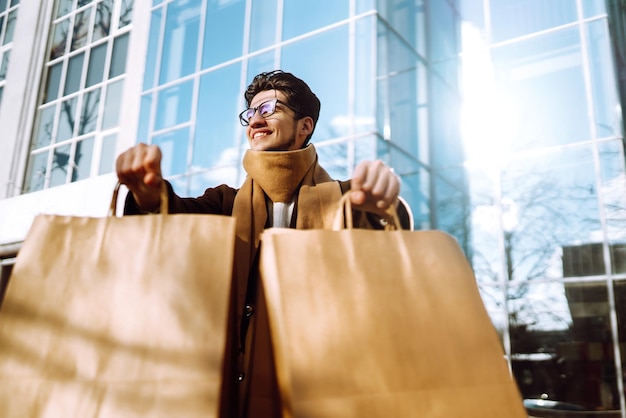 Uomo alla moda con pacchetti di carta dopo lo shopping concetto di stile di vita consumista di vendita