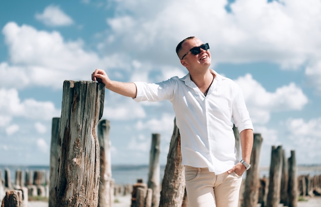 Stylish man with sunglasses posing on the beach